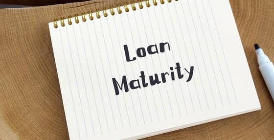 An open notebook sitting on a desk, with “Loan Maturity” written on the first page in black ink. 